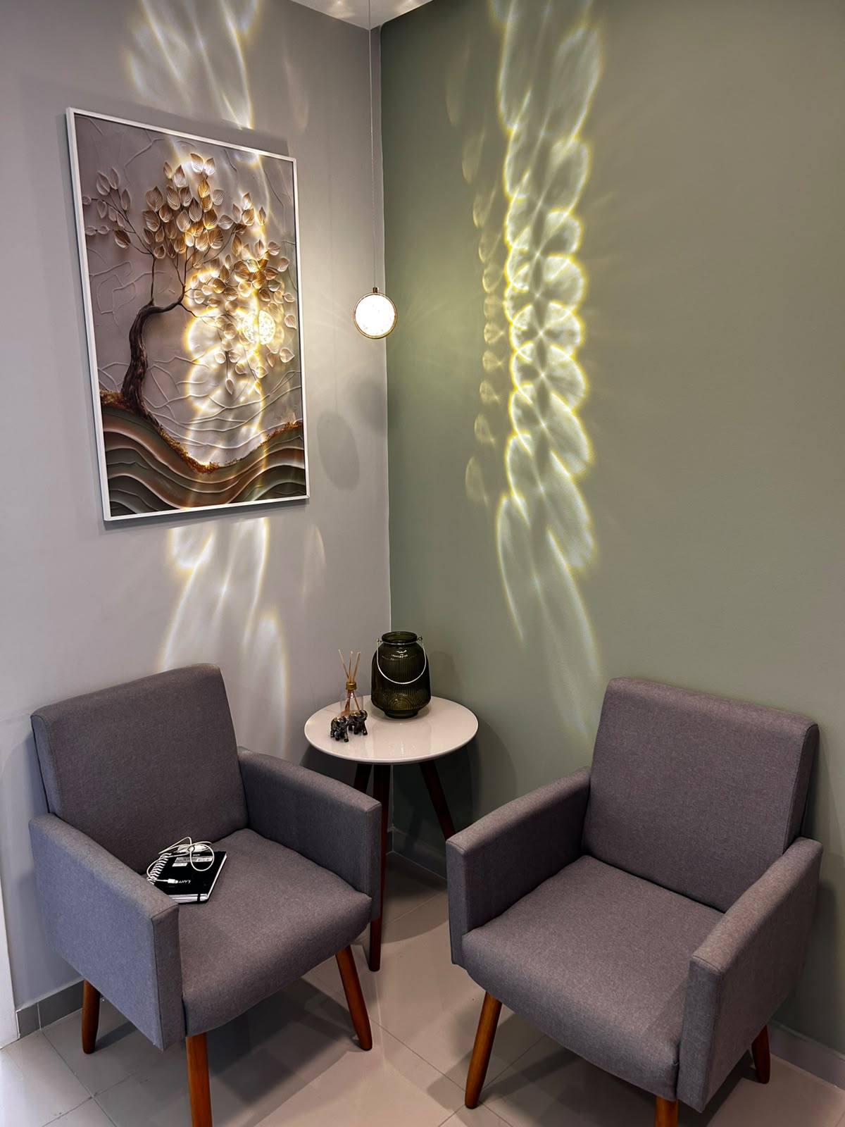 Sala de atendimento com poltronas cinza e quadro decorativo
